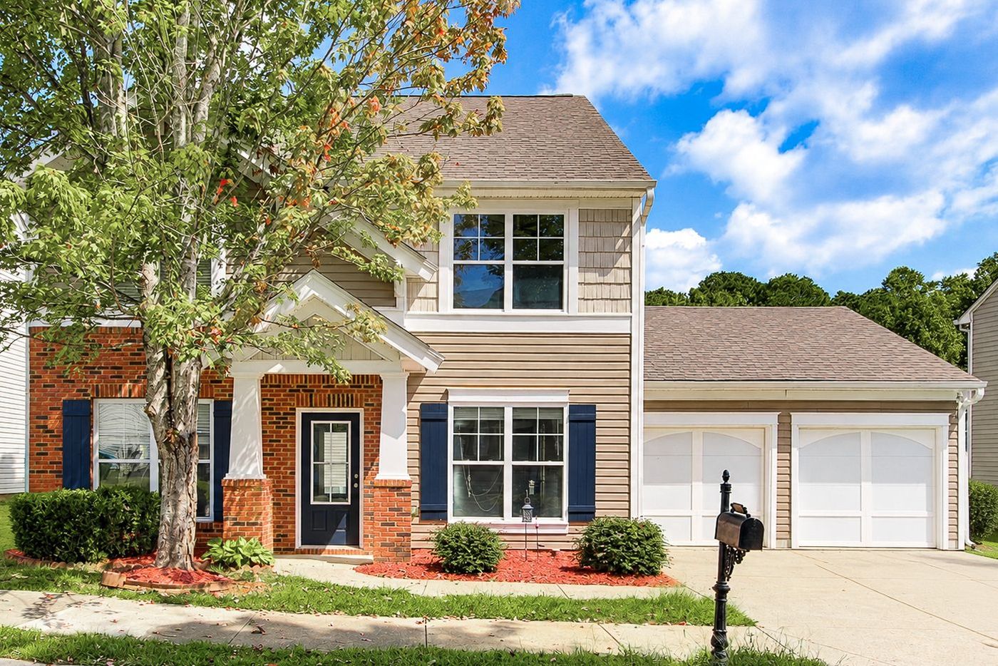 Brick and siding two-story home with navy shutters