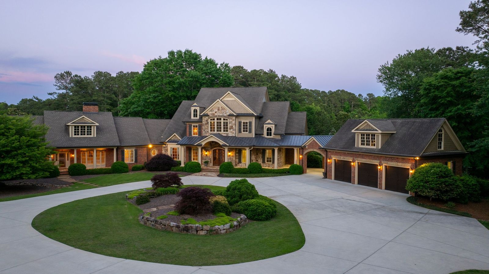 The estate at dusk with every window lit and a circular drive